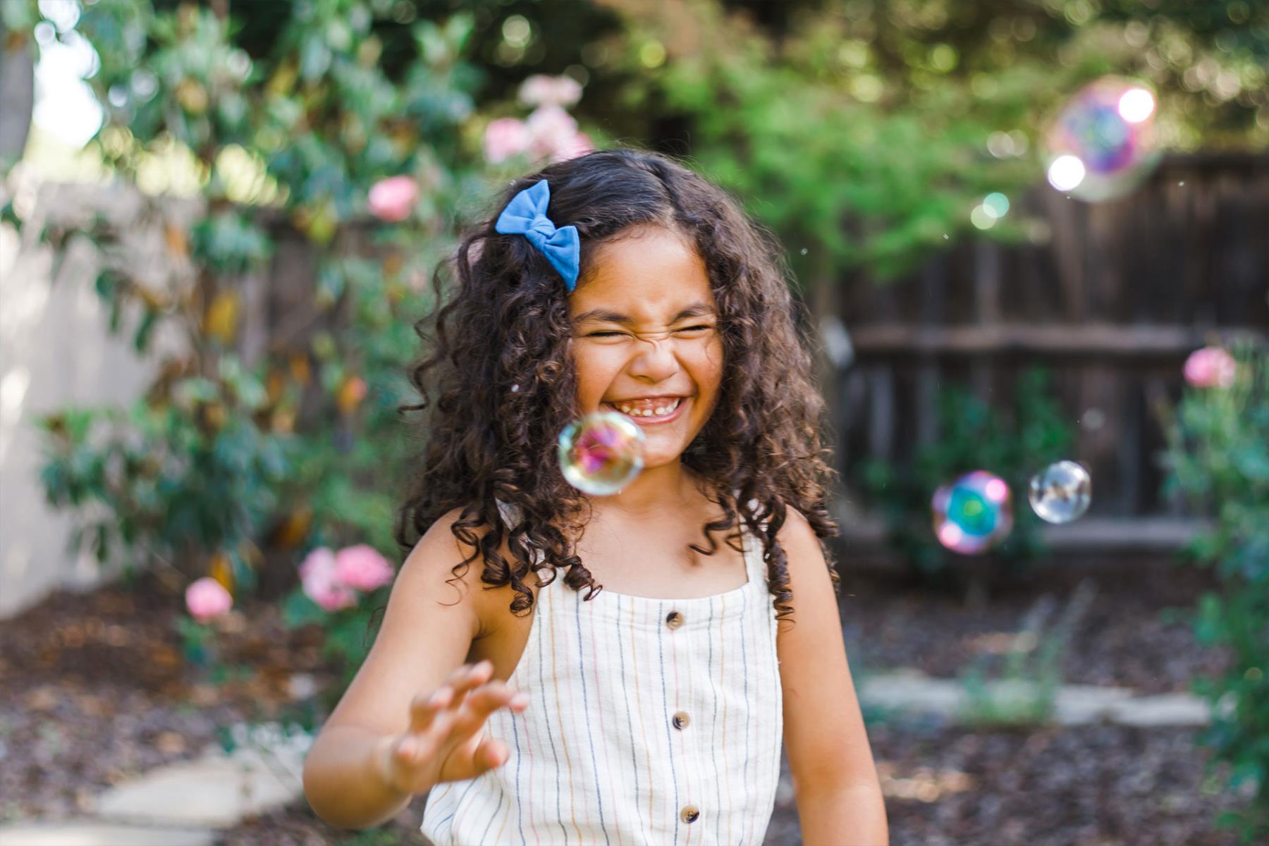 Female child laughing and playing with bubbles outside