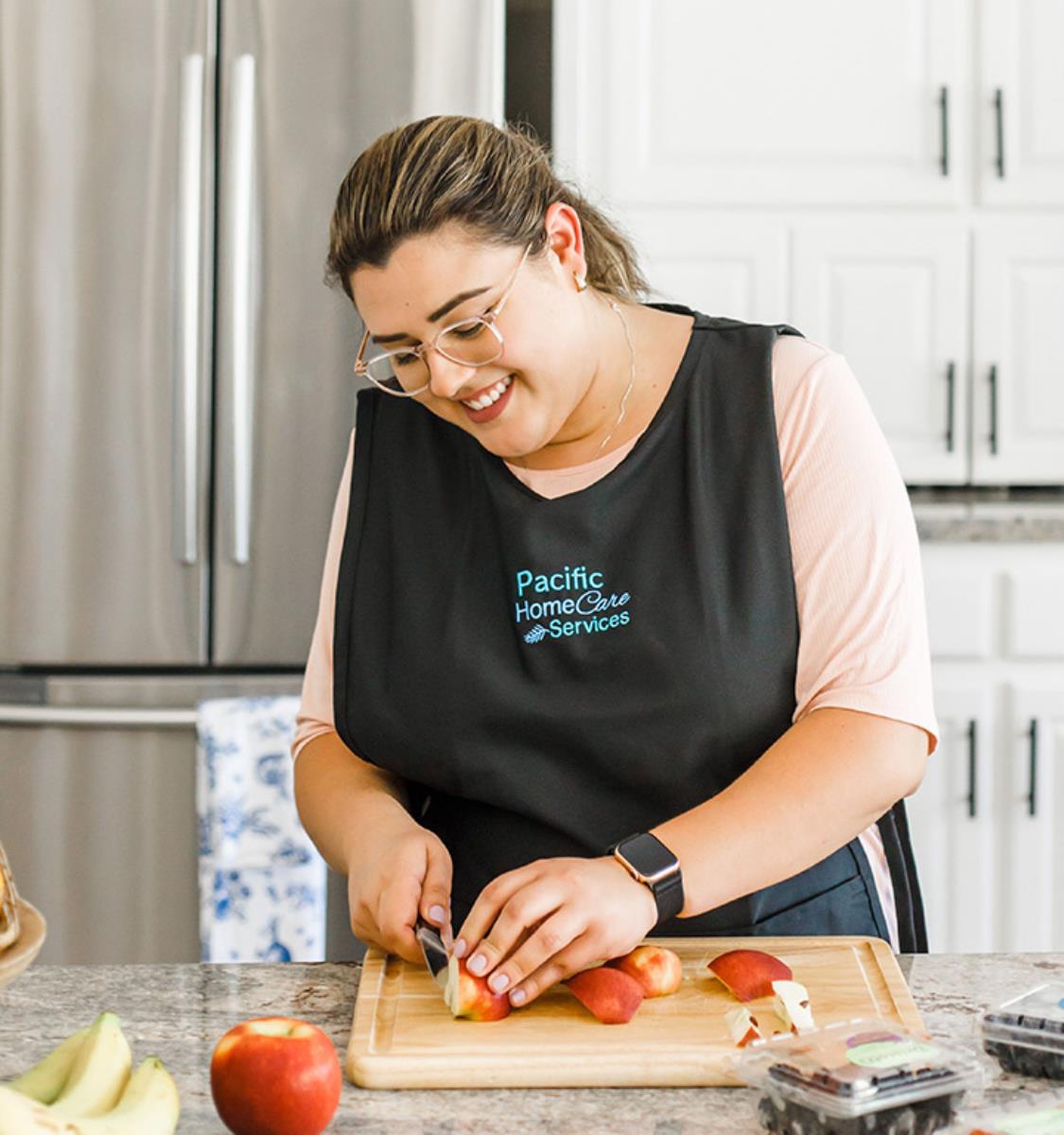 Female care provider cutting an apple in the kitchen on a cutting board